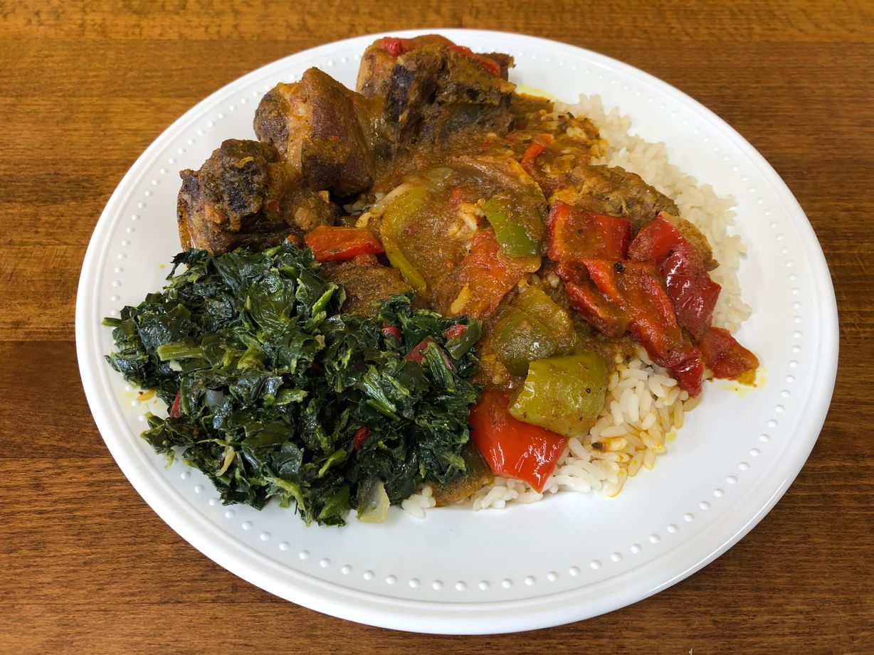 Curry goat w/ rice & a side at Jodeem African Cuisine in Greenbelt, MD 20770 | YourMenu® Online Ordering